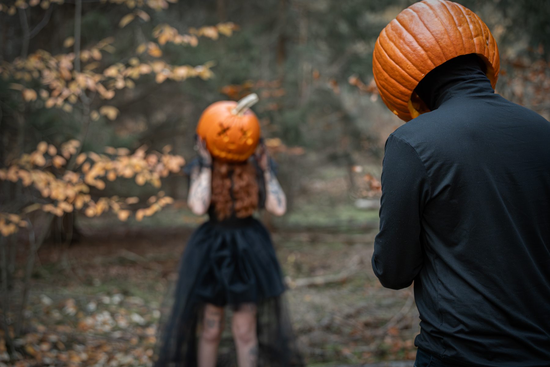 Zwei Personen mit geschnitzten Kürbisköpfen im herbstlichen Wald